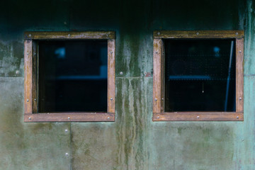 Two copper-trimmed square windows on a verdigris wall