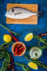 Dorado fish with spices ready to cook on blue background top view