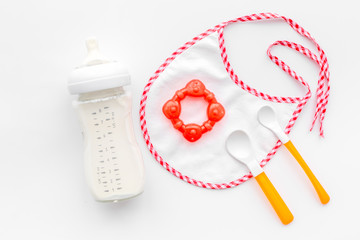 preparation of mixture baby feeding with infant formula powdered milk in bottle with bib on white...