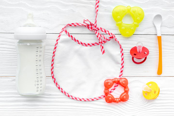 bottle with breastmilk and infant formula powdered healthy food, toys and bib on wooden background...