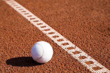 tennis ball on ash court with line