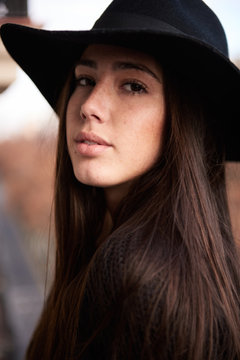 Close-up of attractive young woman in black large hat