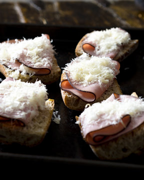 Several sandwiches with ham and cheese on baking tray