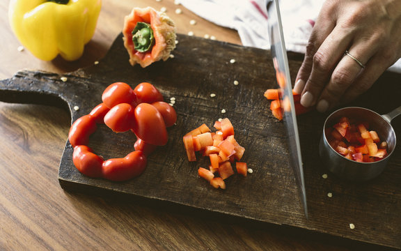 Housewife cutting red pepper on board in kitchen