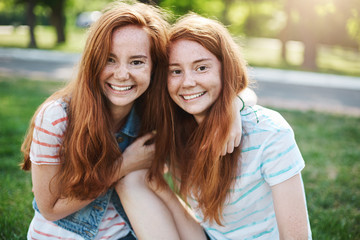 Portrait of identical ginger twin sisters smiling and having fun. Red haired rascals taking the best of their life. Friendship and youth concept. - obrazy, fototapety, plakaty