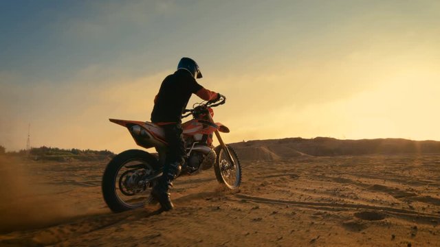 Following Shot of the Professional Motocross Driver Riding on His FMX Motorcycle on the Extreme Off-Road Terrain Track. Shot on RED EPIC-W 8K Helium Cinema Camera.