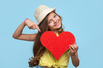 Girl pointing at heart on blue