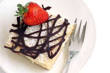 isolated slice of decorated with chocolate and strawberry napoleon cake, served on white plate