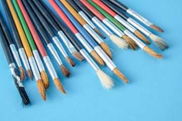 Row of artist paint brushes close up on blue  background
