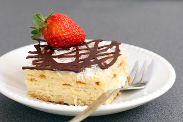slice of decorated with chocolate and strawberry napoleon cake, served on white plate