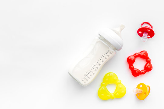 preparation of mixture baby feeding with infant formula powdered milk in bottle with toys. white background top view mockup