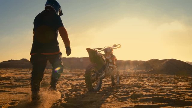 Low Angle Shot of the Professional Motocross Driver Saddles His FMX Dirt Bike on the Sand/ Dirt Track. Shot on RED EPIC-W 8K Helium Cinema Camera.