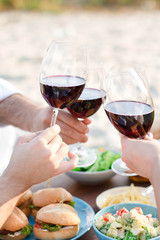      Hands Friends toasting red wine glass and having fun outdoors.