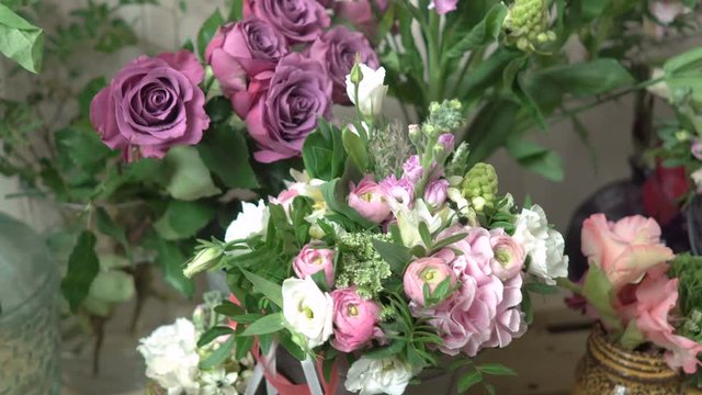 Banks, pots, buckets with flowers on a wooden counter of pallets in a flower shop close-up 4k.