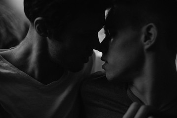 Young gay couple about to kiss in bedroom