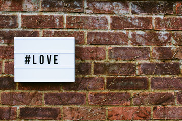 love spelled out on a cinematic light box on an old brick wall