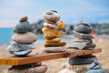 Three pyramids of stones laid out on wooden board at the seashore