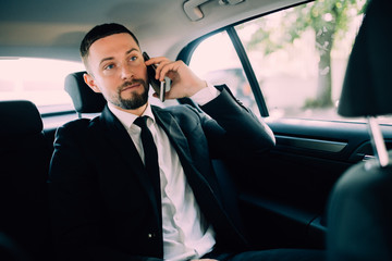 Handsome Businessman working in the backseat of a car