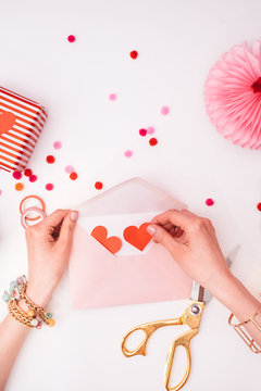 Woman Putting Red Hearts in a Pink Envelope