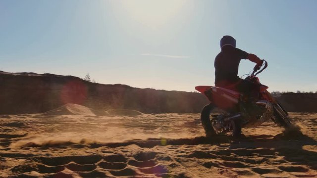 Professional Motocross FMX Motorcycle Rider Drives in Circles on the Off-Road Deserted Quarry. Shot on RED EPIC-W 8K Helium Cinema Camera.