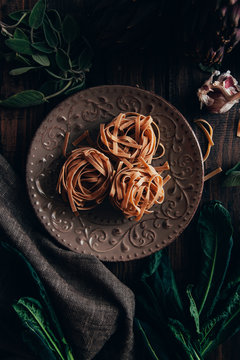 Raw pasta in a plate on dark background