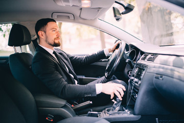 Handsome businessman in the drivers seat in his car and change speed