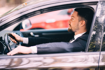 Portrait of young businessman driving a car