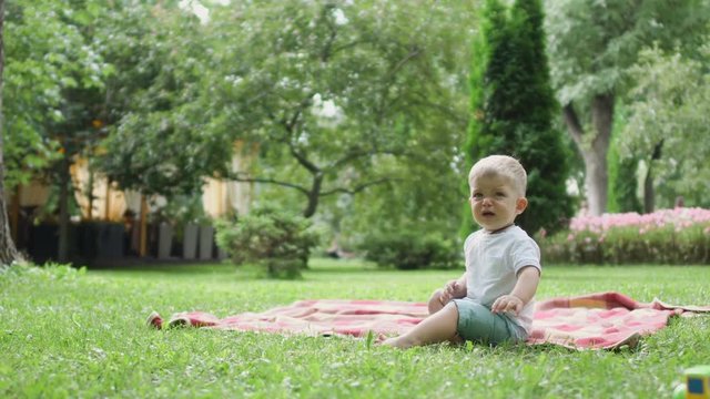 Little boy whines in the park sitting on plaid
