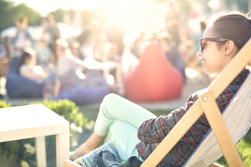 young smiling woman in sun glasses sitting in a lounge chair at a picnic on a bright sunny day