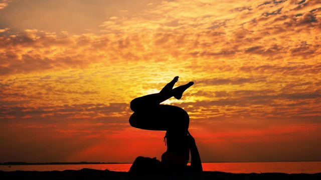 Female silhouette doing yoga asana in slowmotion at sunrise