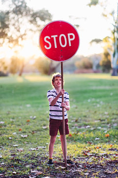 Boy with a stop sign in a park in autumn