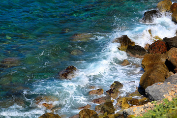 Turquoise beautiful sea wave background on the stones near the shore and foam. Contrast portrait