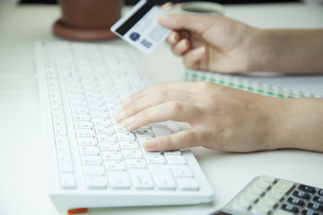 Woman hands holding a credit card and using computer keyboard