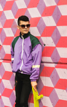 Wild kids/portrait hip young male in trendy outfit in front of colorful patterned wall.