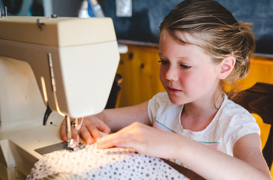 Young girl sewing fabric on a sewing machine