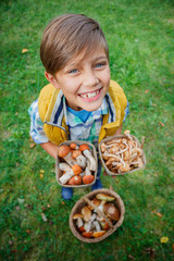 Cute boy with wild mushroom found in the forest