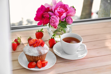 Delicious muffin and cup of tea on windowsill