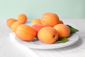 Plate with fresh apricots on wooden table