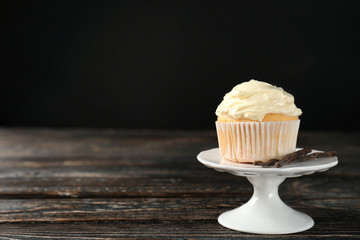 Dessert stand with tasty vanilla cupcake on black background