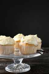 Dessert stand with tasty vanilla cupcakes on black background