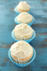 Tasty vanilla cupcakes on wooden table