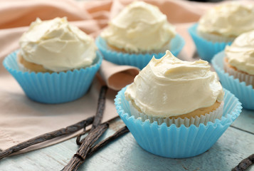 Tasty vanilla cupcakes on wooden table