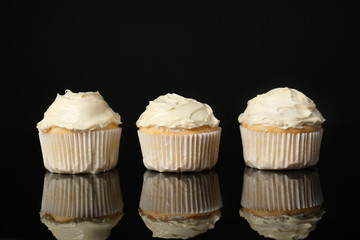 Tasty vanilla cupcakes on black background