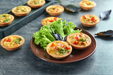 Plate with broccoli quiche tartlets on table