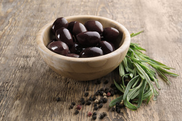 Bowl with red olives on wooden table