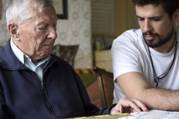 Grandfather and his grown up grandson sitting and having a conversation inside the living room