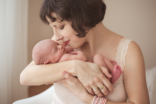 Portait of a beautiful young mother snuggling with her newborn baby