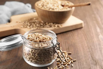 Fototapeten Jar with wheat grains on wooden table © Africa Studio