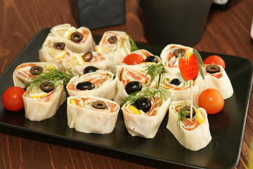 Salmon lavash rolls with cheese, olive, tomato and herbs