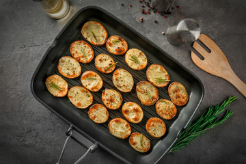 Grill pan with delicious baked potato slices on table